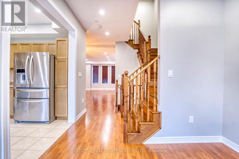 A spacious kitchen with a refrigerator and a staircase.