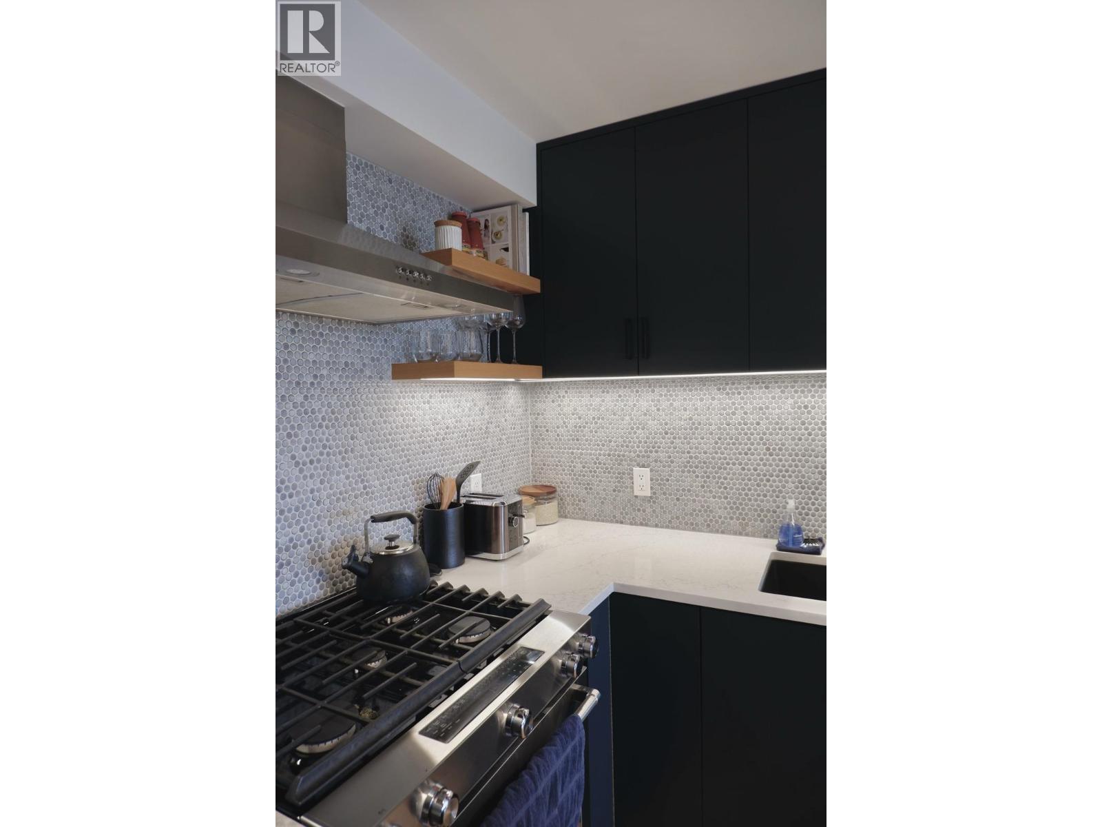 A kitchen with a stove top oven and black cabinets.