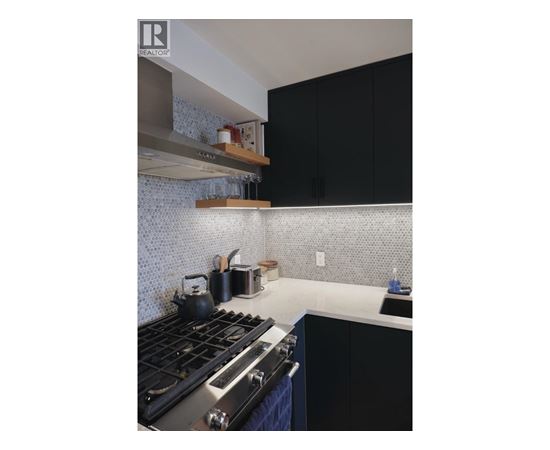 A kitchen with a stove top oven and black cabinets.