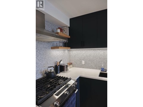 A kitchen with a stove top oven and black cabinets.