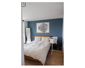 A bedroom with a white bed and a white chair.