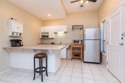 A kitchen with white cabinets and a stainless steel refrigerator.