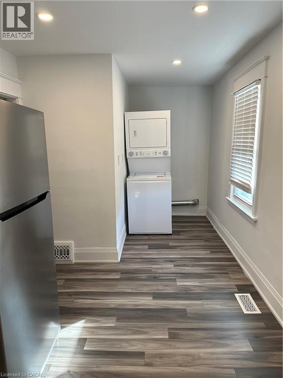 A kitchen with a refrigerator and a washer and dryer stacked on top of each other.