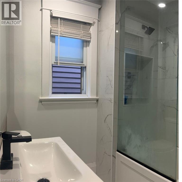A bathroom with a sink, mirror, and window with blinds.