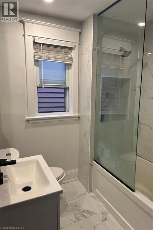 A bathroom with a sink, toilet, and a window.