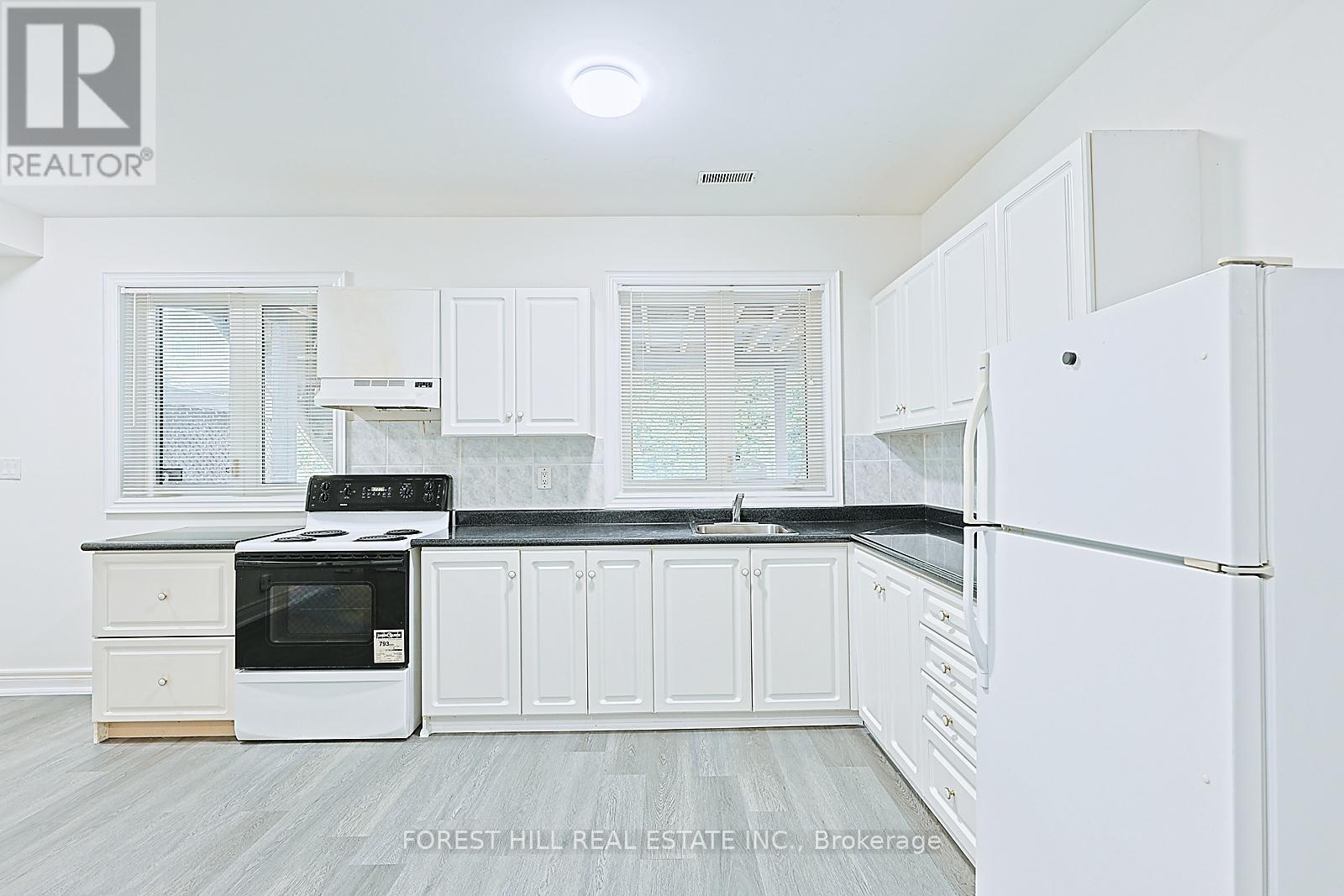 A kitchen with white cabinets and a black countertop.