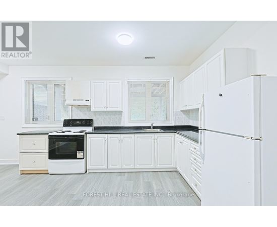 A kitchen with white cabinets and a black countertop.