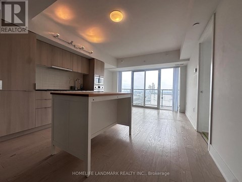 A spacious kitchen and living room with wooden flooring and white walls.