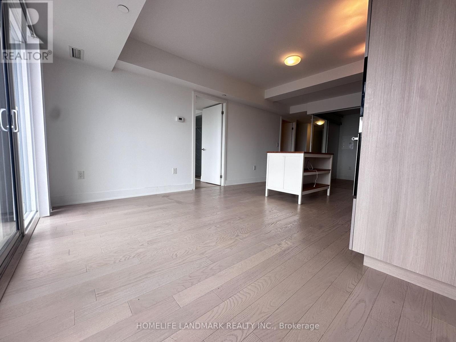 A spacious room with wooden flooring and white walls.