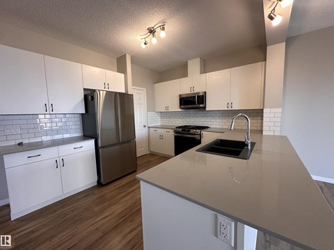 A kitchen with white cabinets and a stainless steel refrigerator.