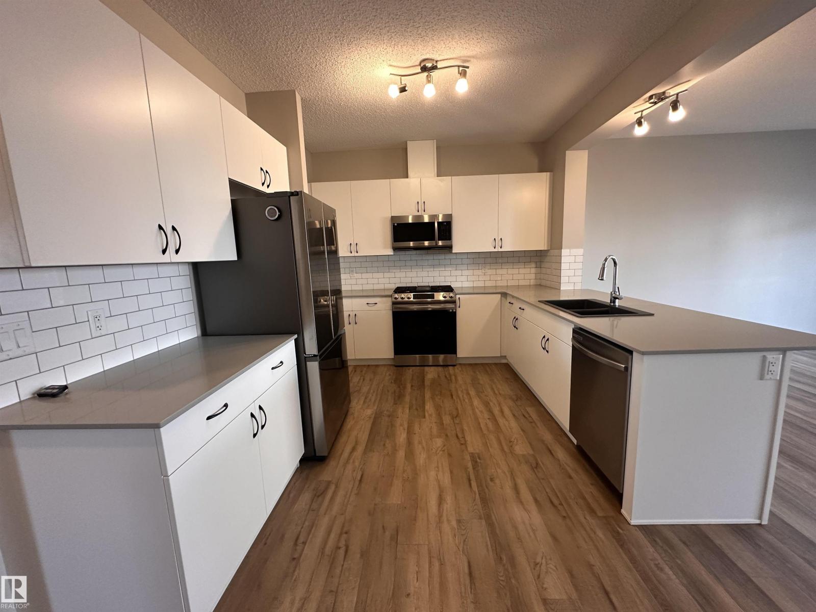 A kitchen with white cabinets and a black fridge.