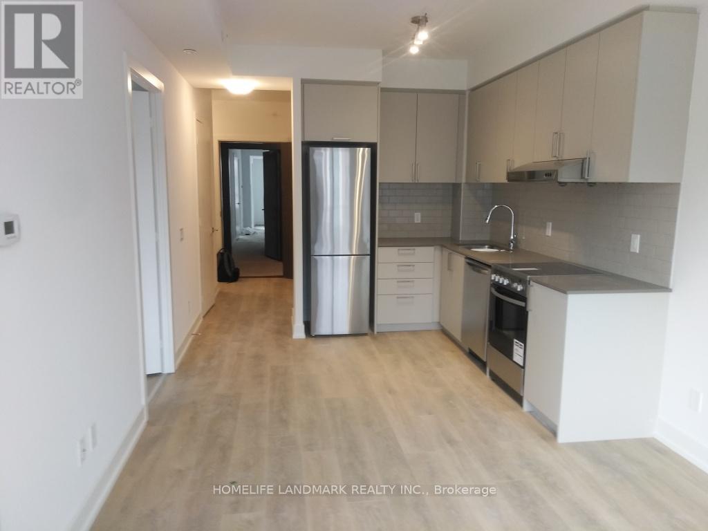 A kitchen with a refrigerator, sink, and cabinets.
