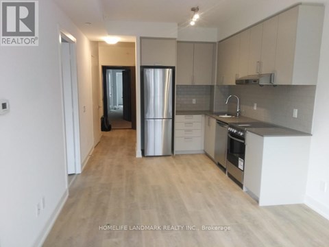 A kitchen with a refrigerator, sink, and cabinets.