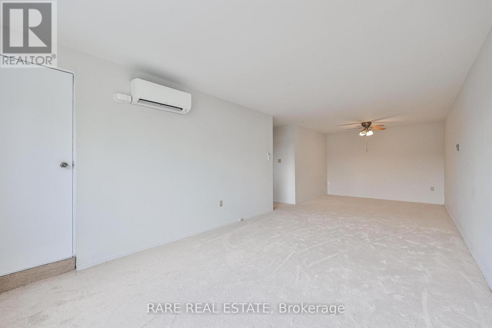 A spacious room with a ceiling fan and an air conditioner unit mounted on the wall.