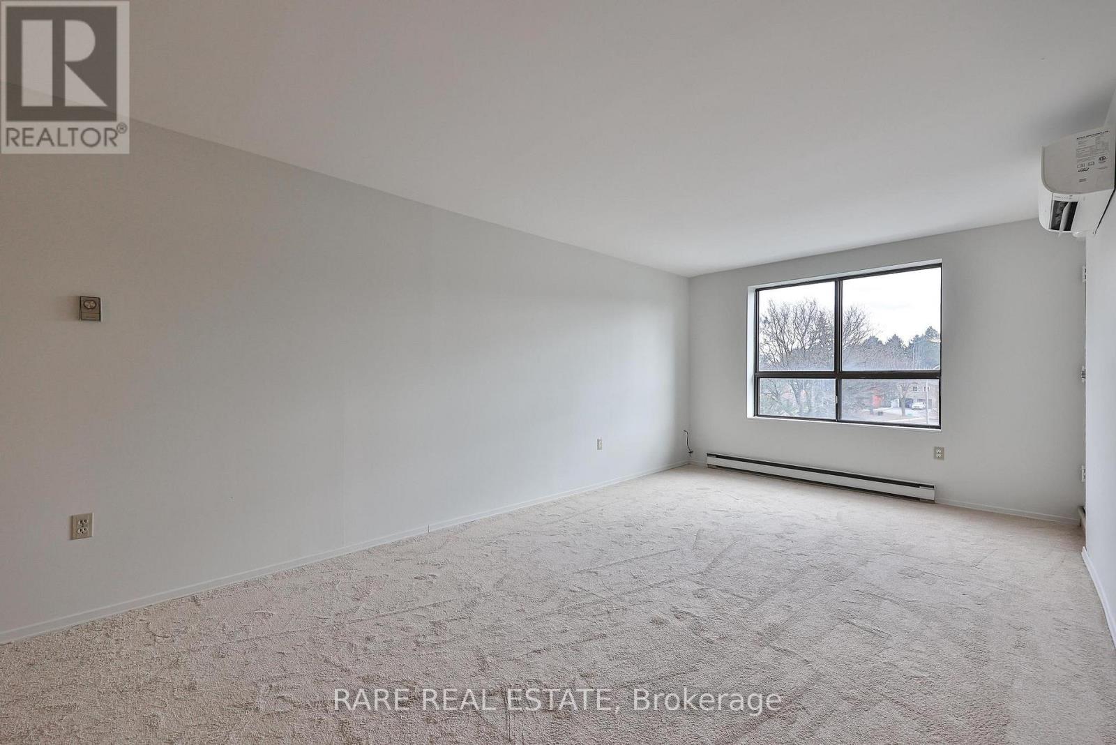 A spacious room with a window and a carpeted floor.