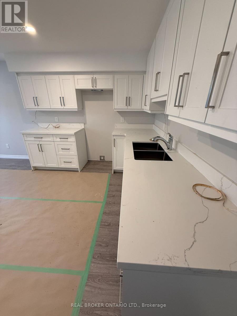 A kitchen under renovation with white cabinets and a green tape on the floor.