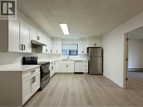 A kitchen with white cabinets and a refrigerator.