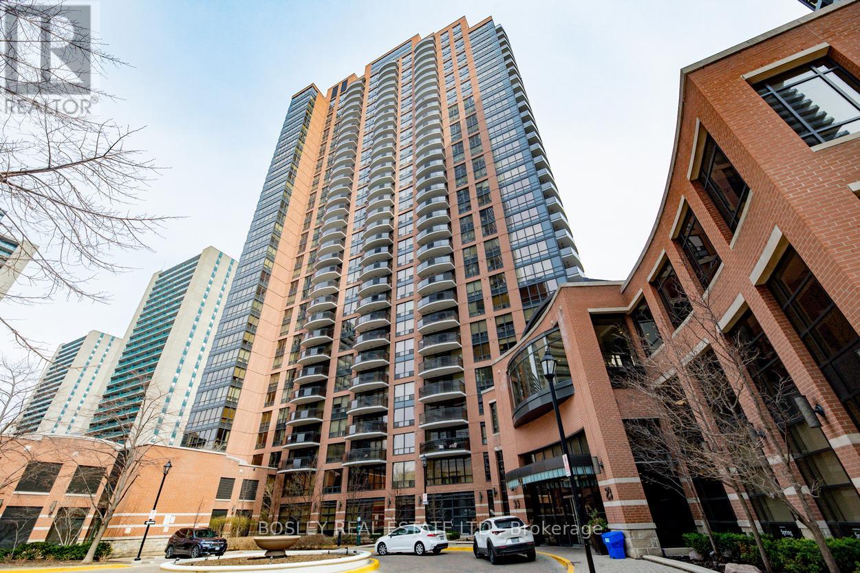 A tall building with a glass facade stands next to a shorter brick building.