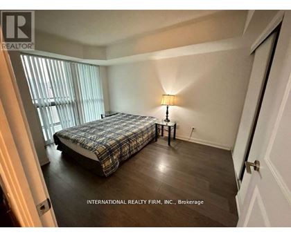A bedroom with a bed, nightstand, and lamp.