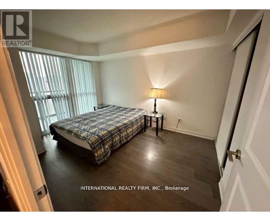 A bedroom with a bed, nightstand, and lamp.