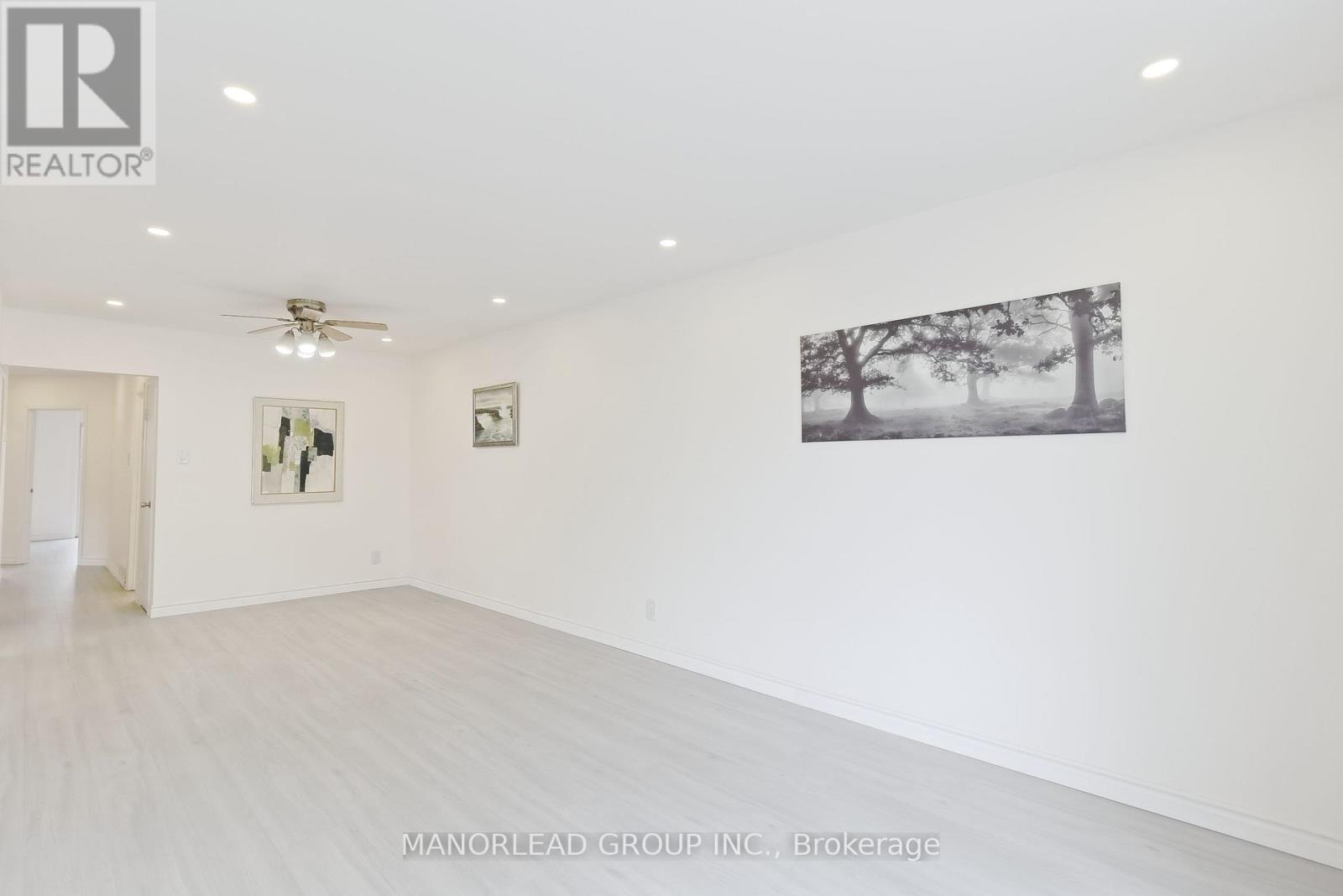 A spacious room with a ceiling fan and a painting on the wall.