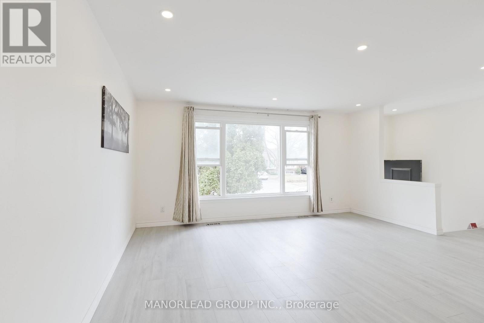 A white room with a large window and a flat screen TV mounted on the wall.