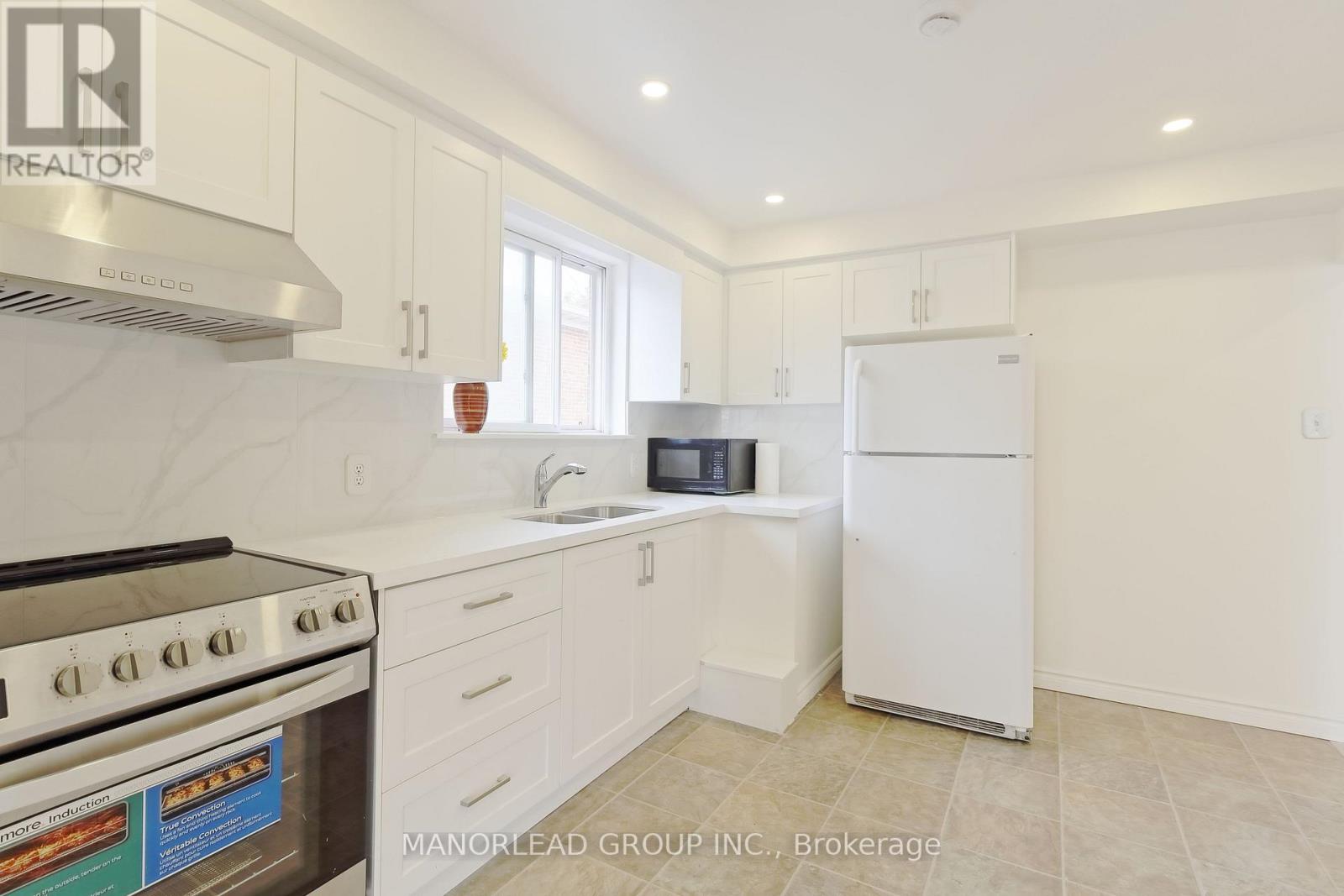 A kitchen with white cabinets and a stove top oven.