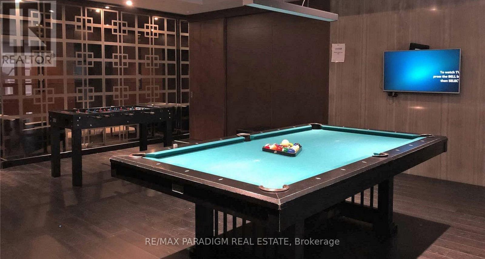 A pool table in a room with a television mounted on the wall.