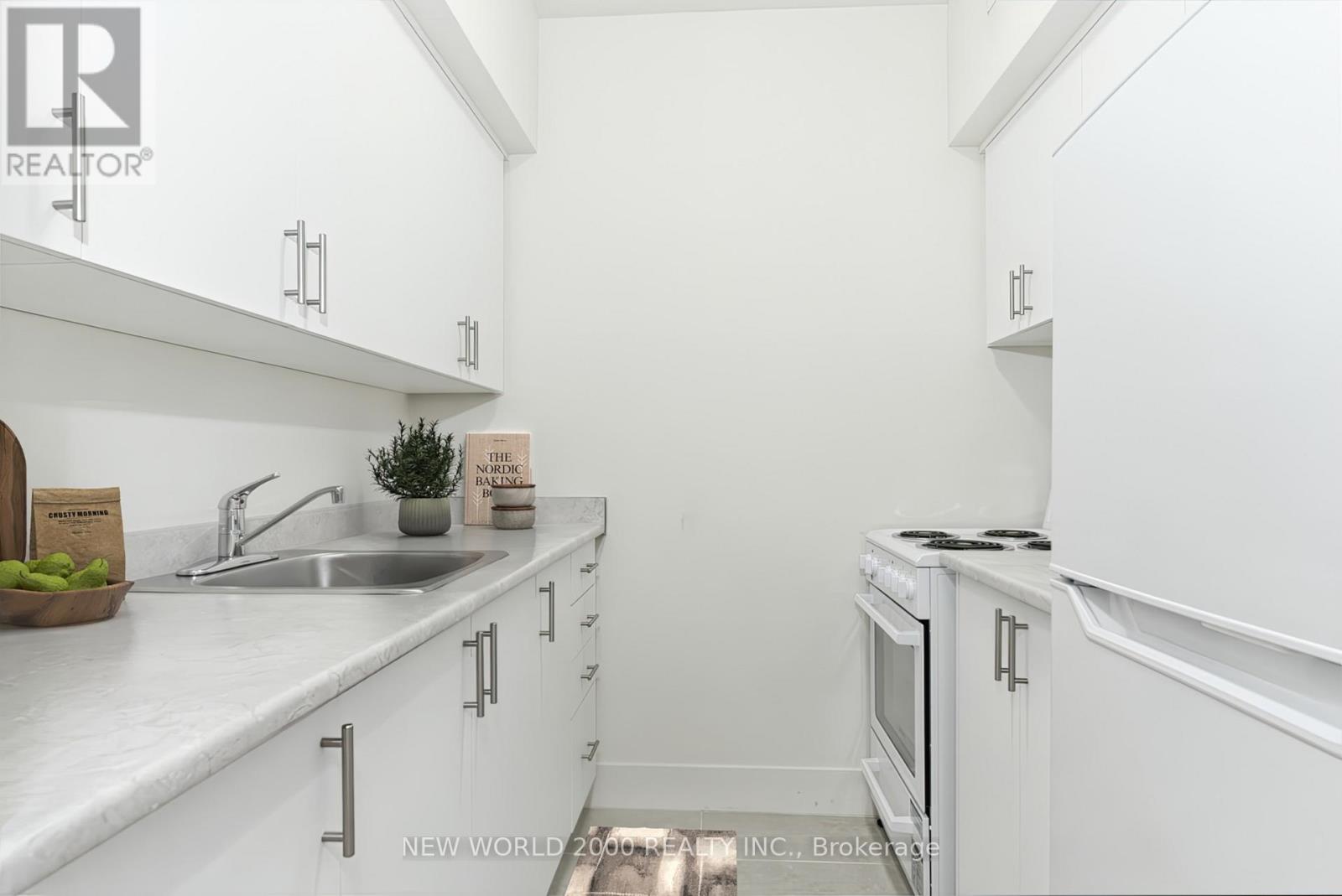 A white kitchen with a sink, stove, and cabinets.