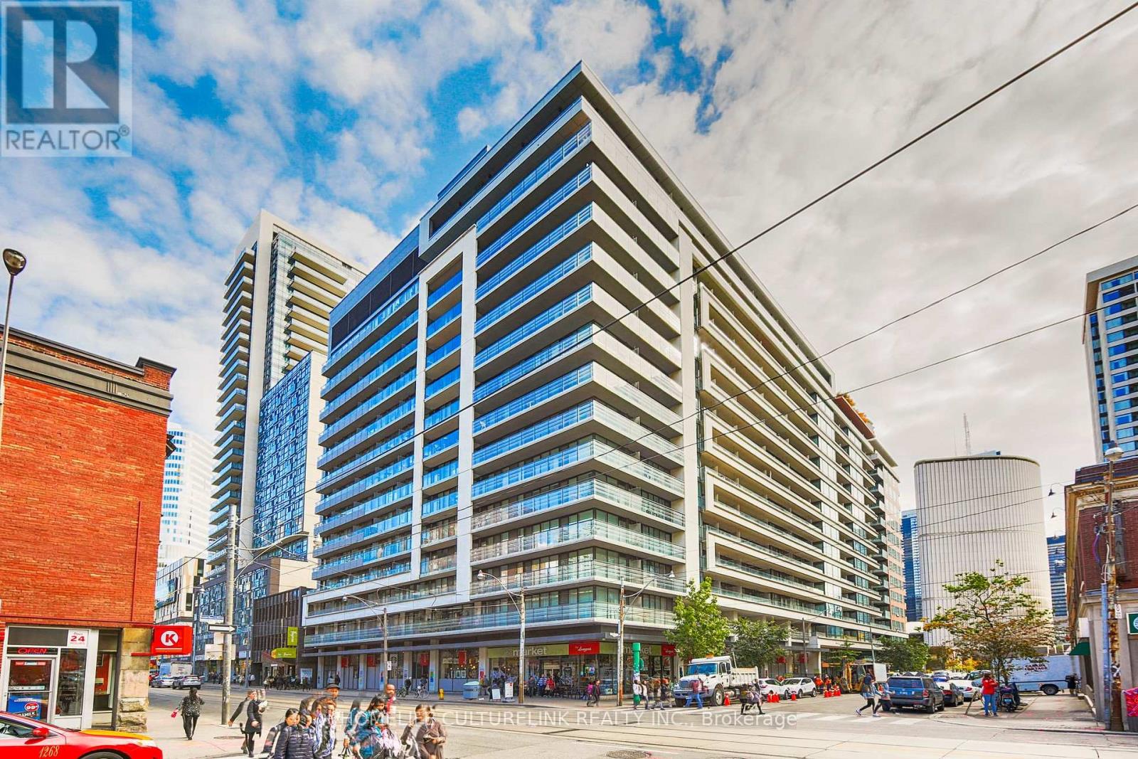 A large, modern building with many windows is the focal point of a bustling city street.