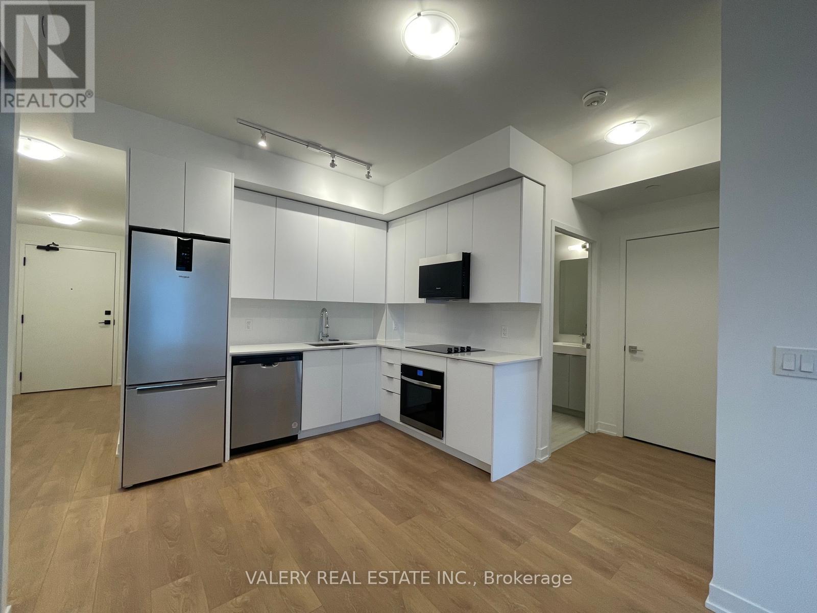 A kitchen with white cabinets and a stainless steel refrigerator.