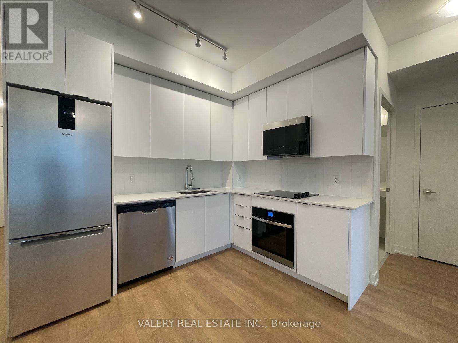 A kitchen with white cabinets and a stainless steel refrigerator.