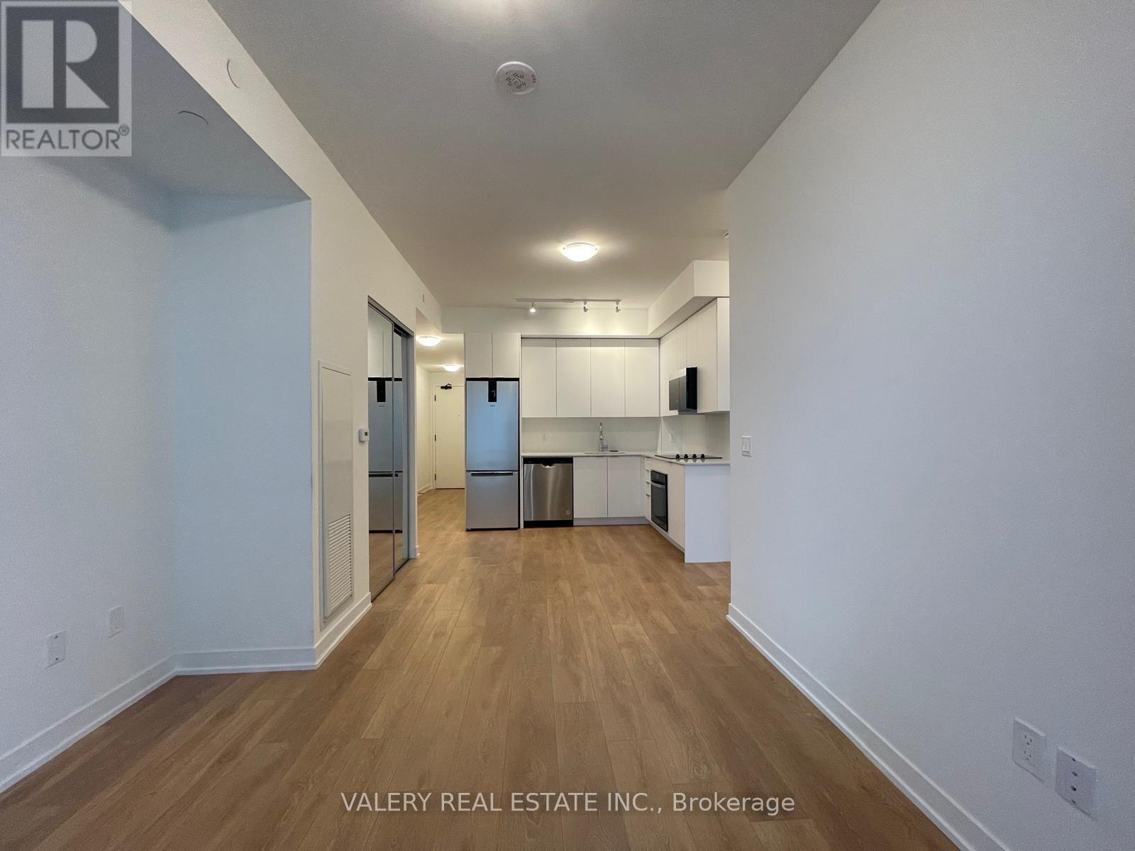 A spacious kitchen with white cabinets and a stainless steel refrigerator.