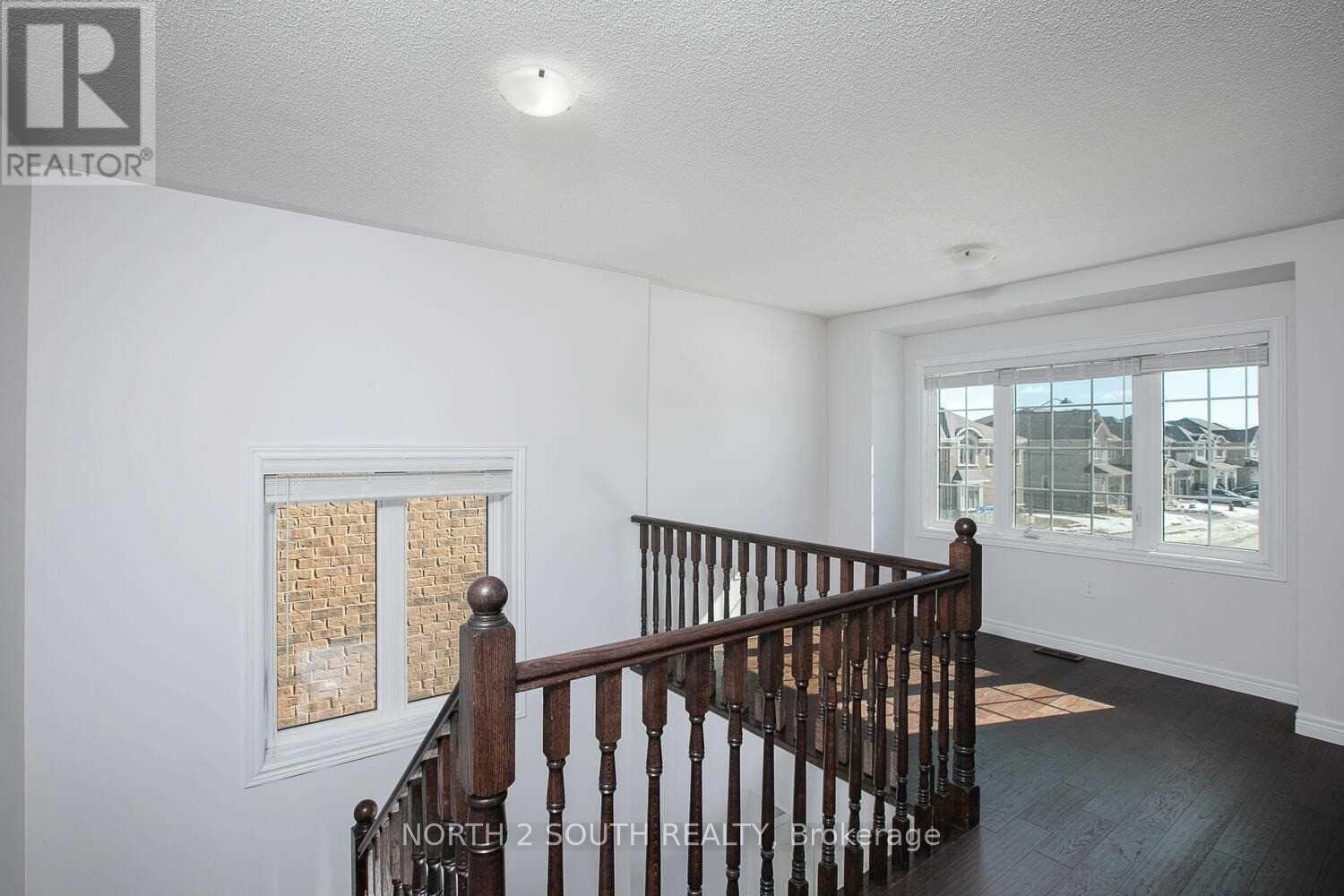 A room with a wooden staircase and a window with a view of a building.