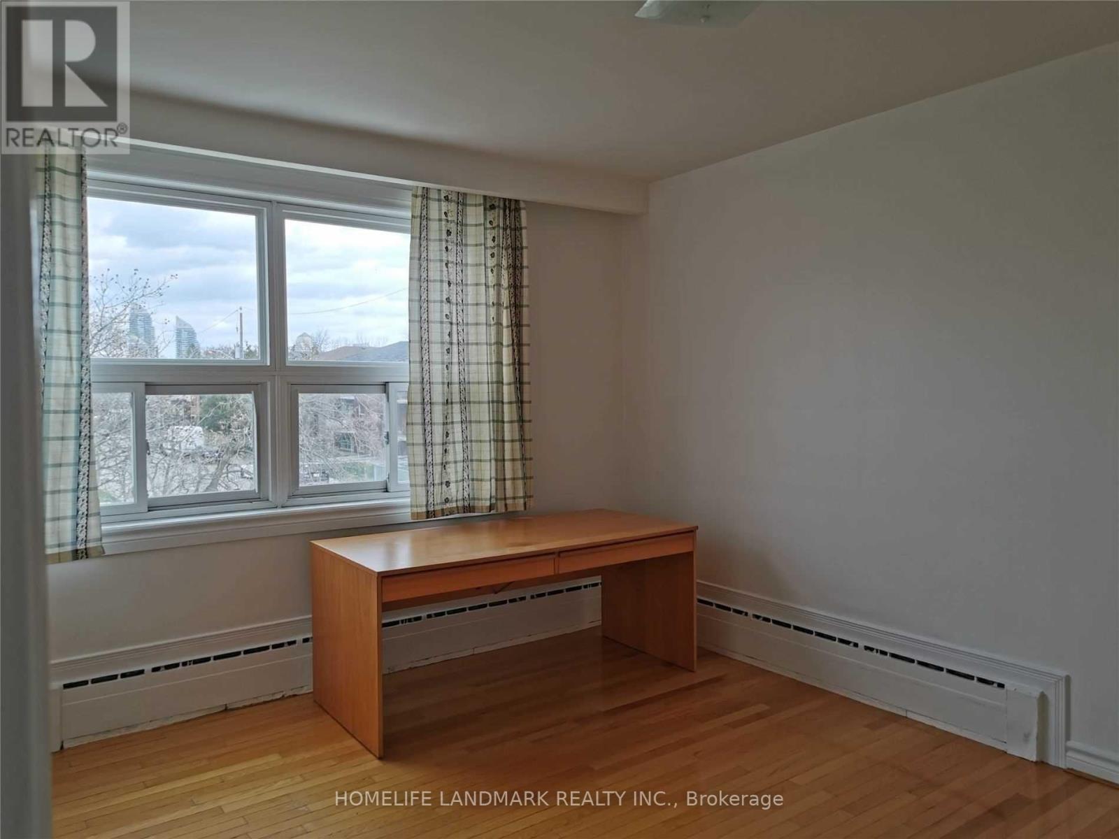 A room with a desk and a window with curtains.