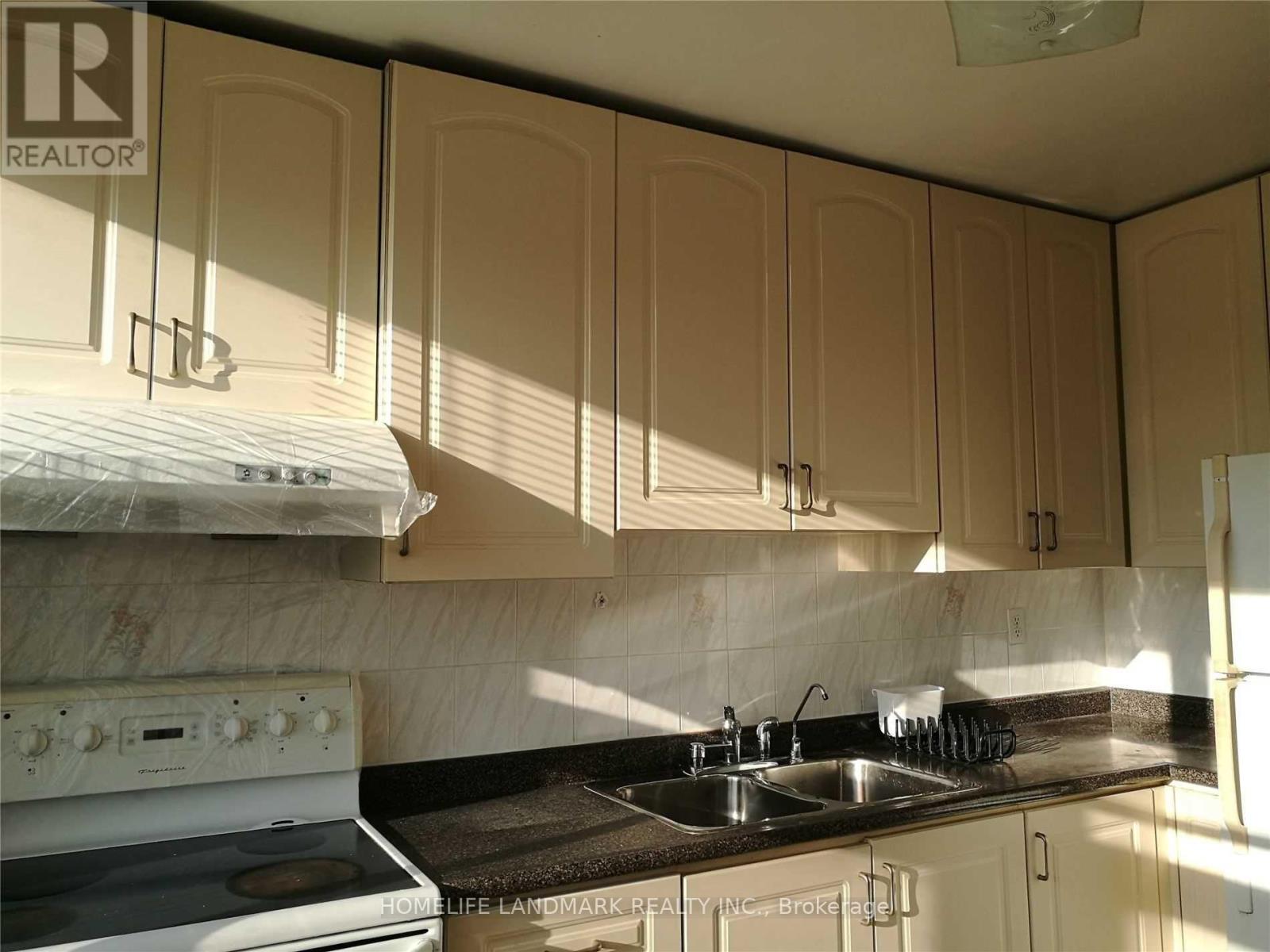 A kitchen with a white stove and beige cabinets.