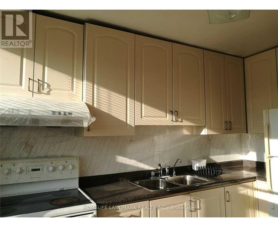 A kitchen with a white stove and beige cabinets.