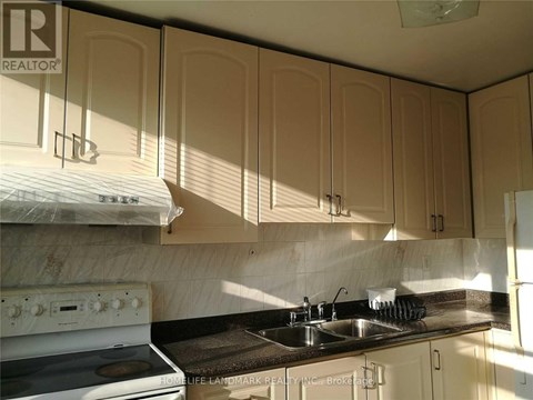 A kitchen with a white stove and beige cabinets.