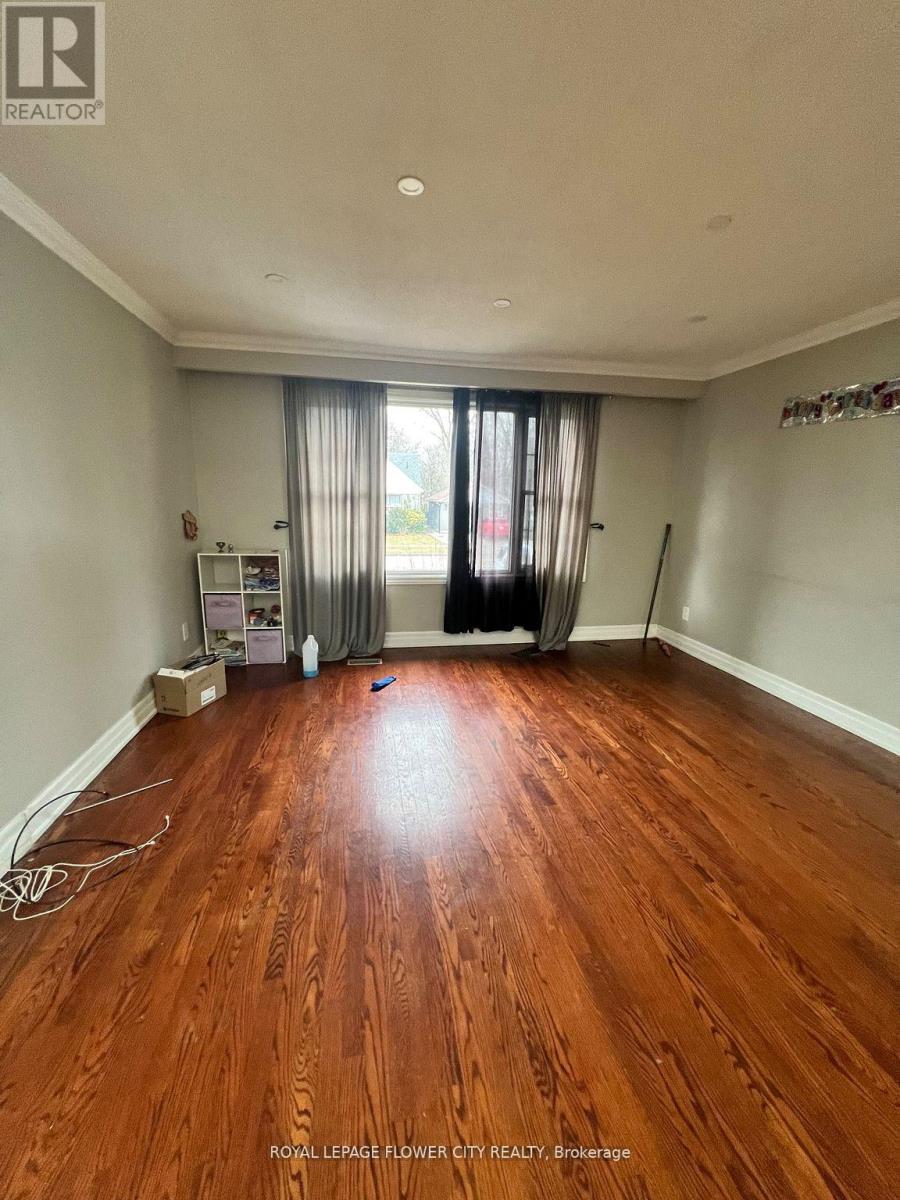 A room with wooden flooring and a window with curtains.