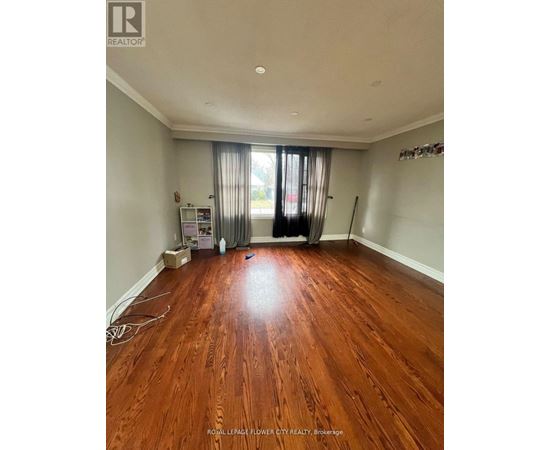 A room with wooden flooring and a window with curtains.