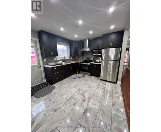 A kitchen with black cabinets and a marble floor.