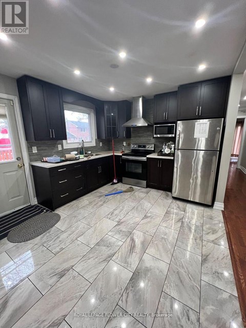 A kitchen with black cabinets and a marble floor.