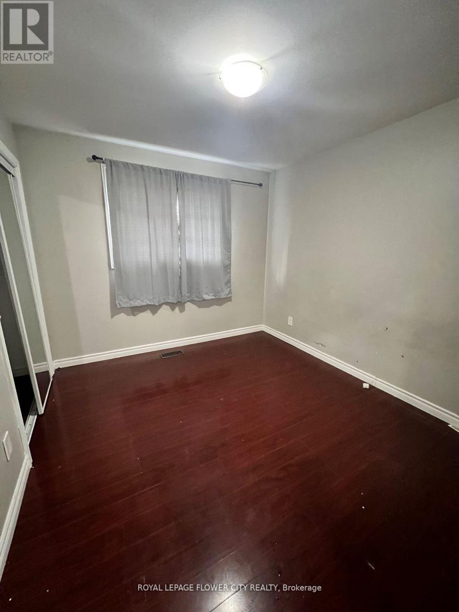 A room with wooden flooring and a window with curtains.