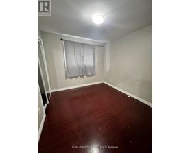 A room with wooden flooring and a window with curtains.