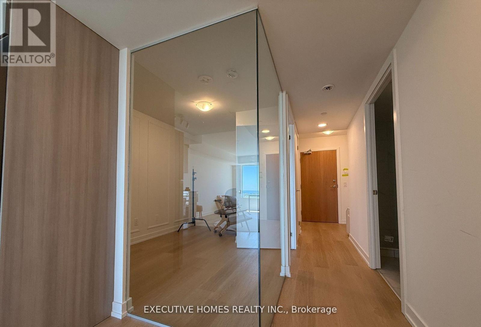 A hallway with a mirrored wall and wooden floors.