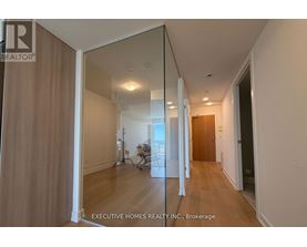 A hallway with a mirrored wall and wooden floors.