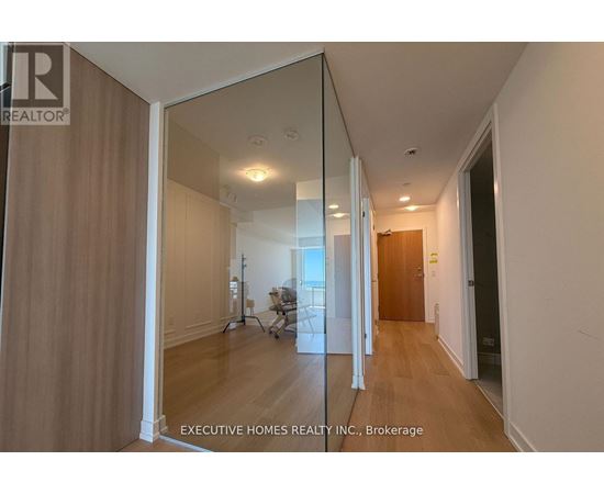 A hallway with a mirrored wall and wooden floors.