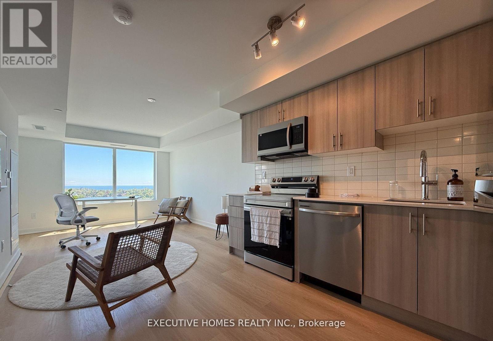 A modern kitchen with wooden cabinets and a large window overlooking the ocean.