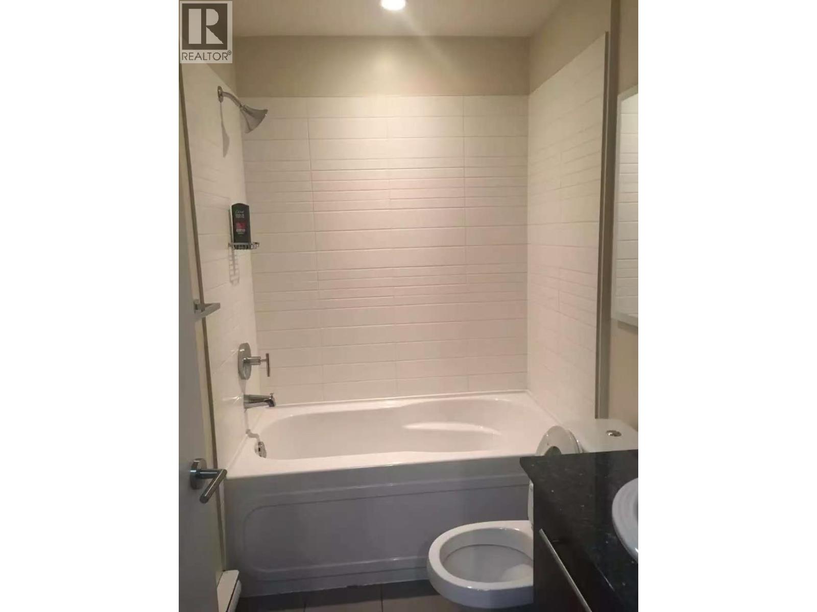 A white bathtub is in a bathroom with a toilet and a sink.