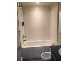 A white bathtub is in a bathroom with a toilet and a sink.